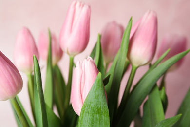 Photo of Bouquet of beautiful spring tulips on light pink background, closeup