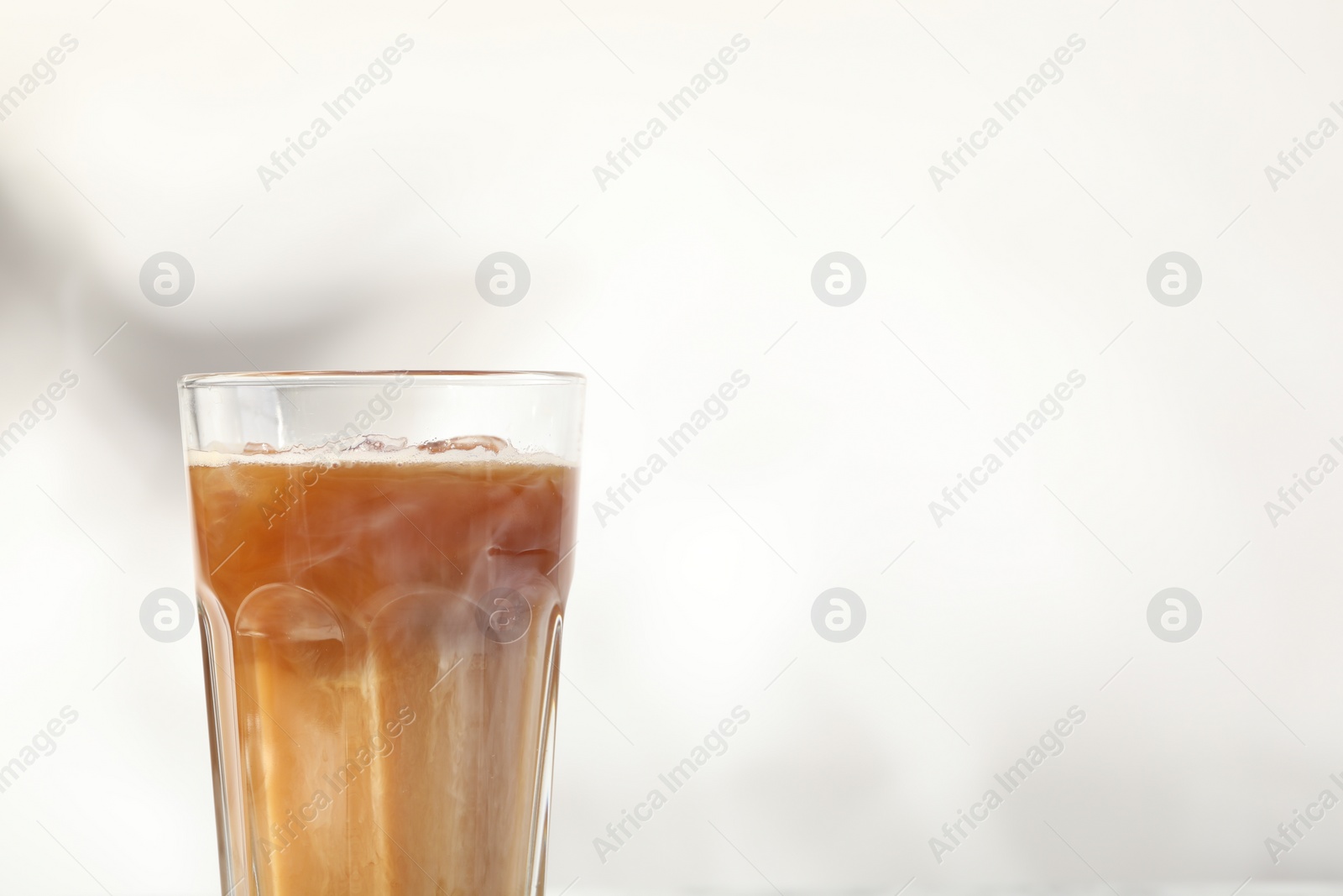 Photo of Refreshing iced coffee with milk in glass on white background, closeup. Space for text