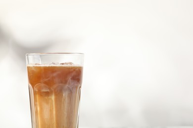 Photo of Refreshing iced coffee with milk in glass on white background, closeup. Space for text