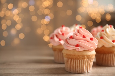 Photo of Tasty sweet cupcakes on wooden table, space for text. Happy Valentine's Day