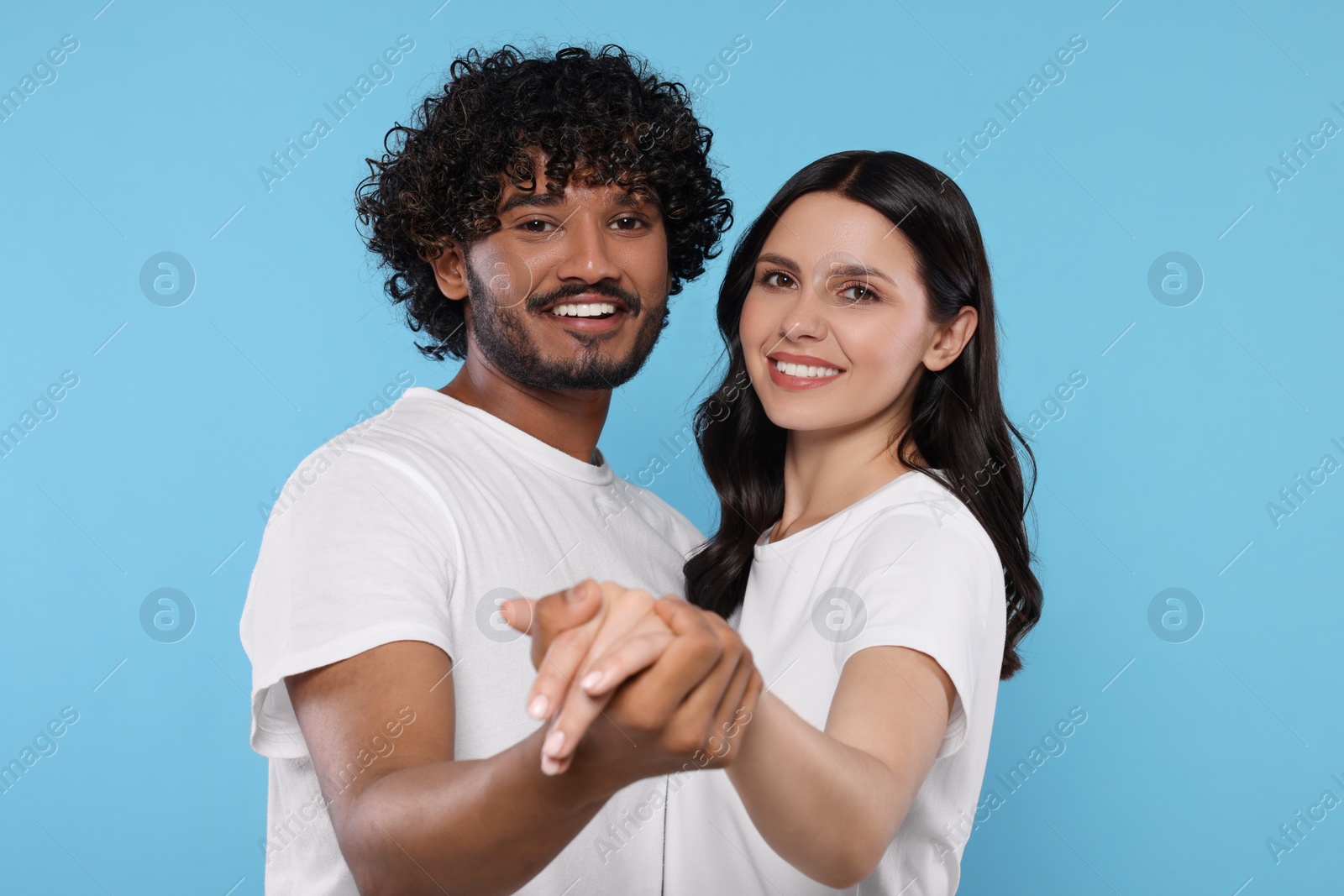 Photo of International dating. Happy couple dancing on light blue background