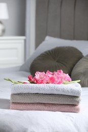 Photo of Terry towels with beautiful flower on bed indoors, space for text