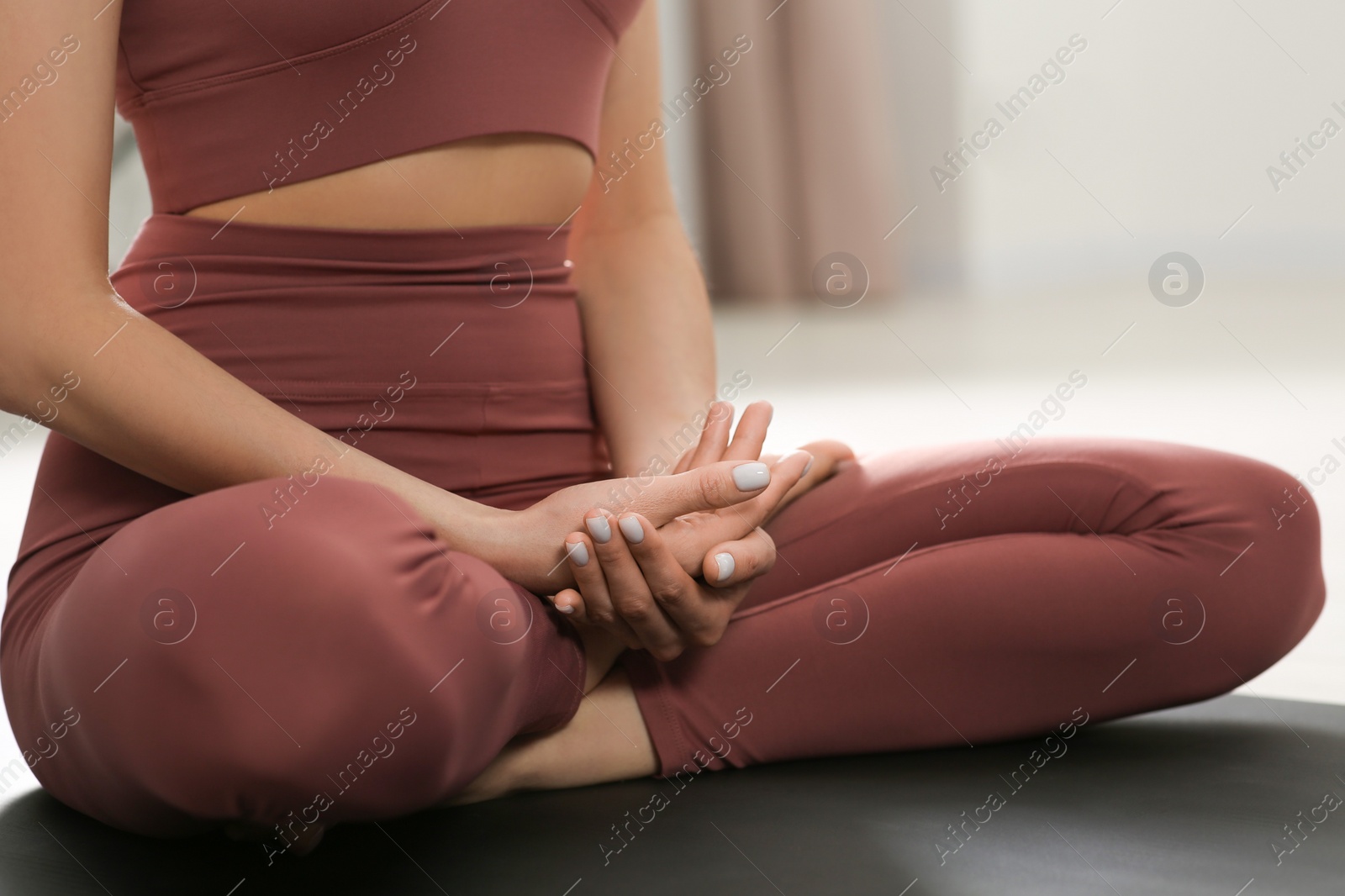 Photo of Woman in sportswear meditating indoors, closeup view