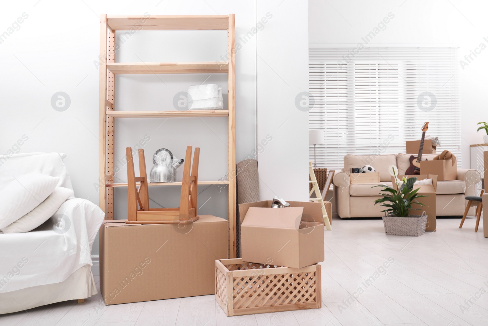 Photo of Cardboard boxes and household stuff in living room. Moving day