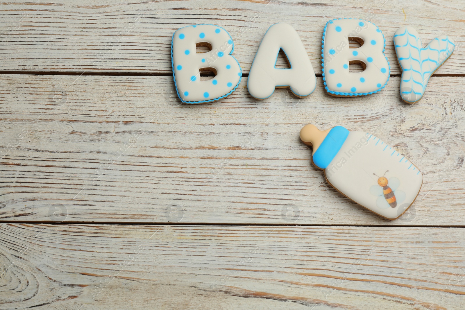 Photo of Word BABY made of tasty cookies on white wooden table, flat lay. Space for text