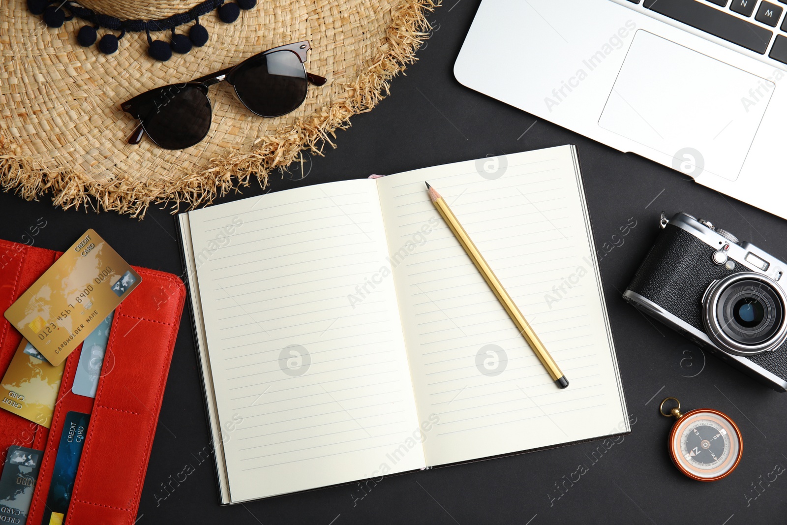 Photo of Flat lay composition with tourist items and notebook on black background, space for text. Travel agency