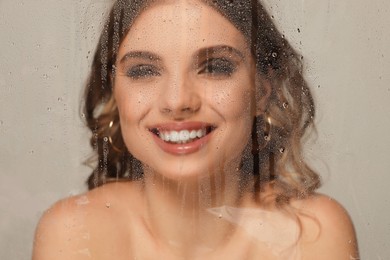 Photo of Beautiful young woman posing through transparent film on grey background