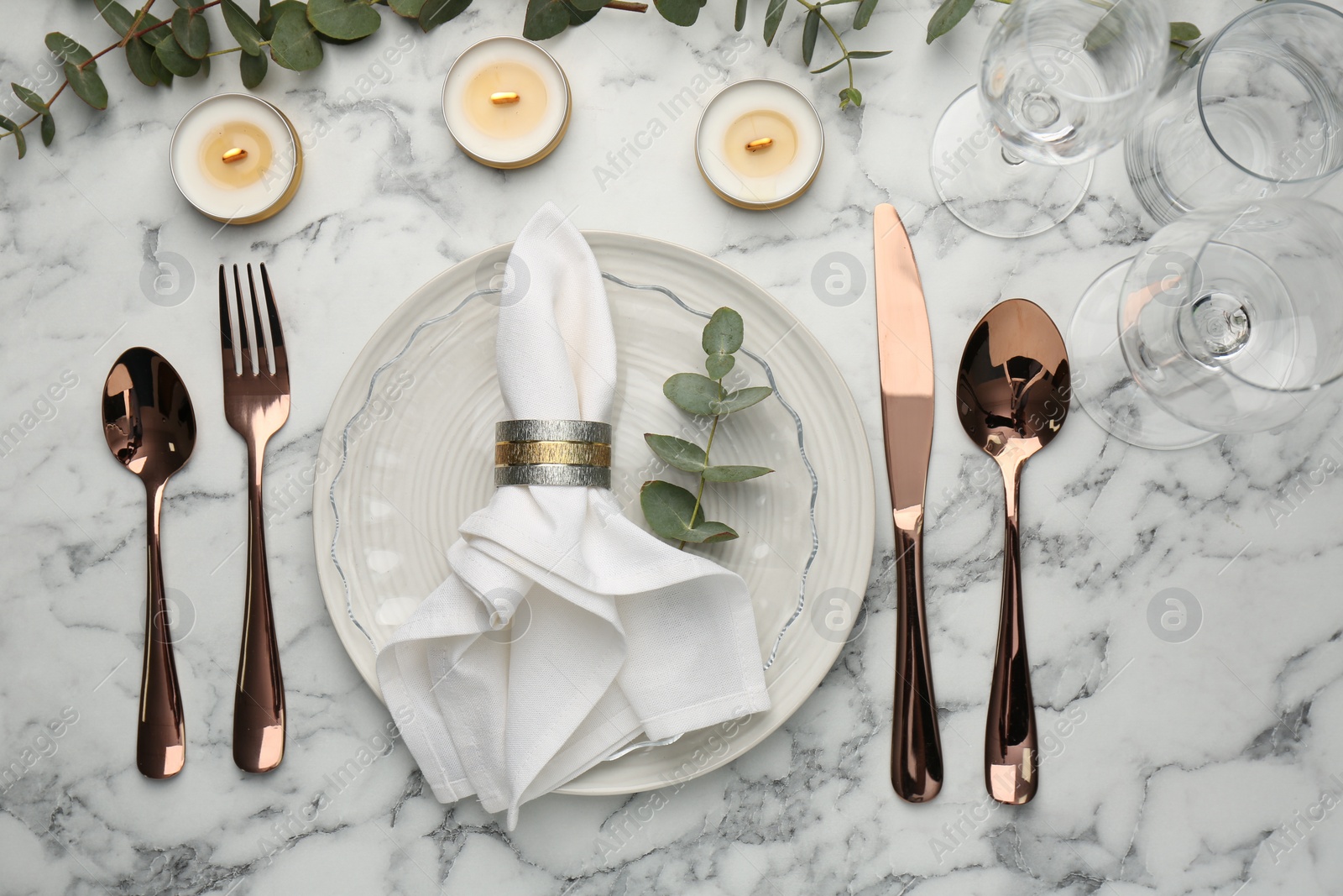 Photo of Beautiful place setting with candles and eucalyptus on white marble table, flat lay