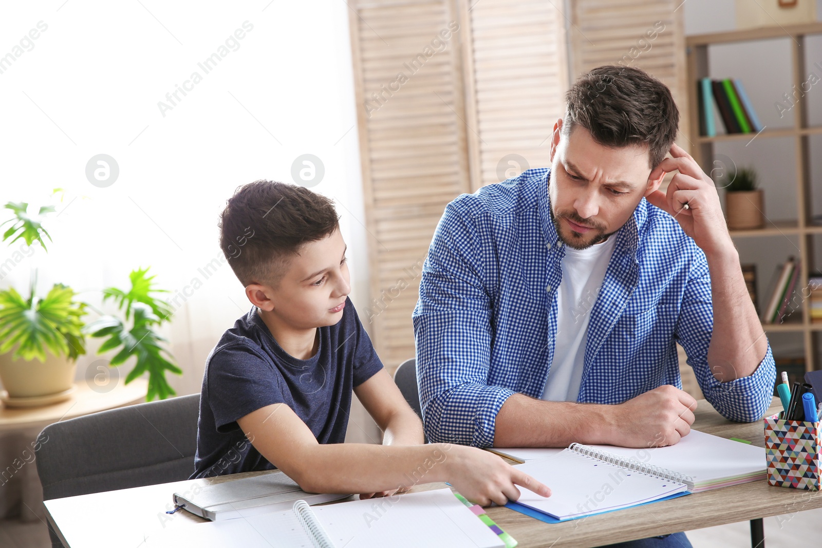 Photo of Dad helping his son with homework in room