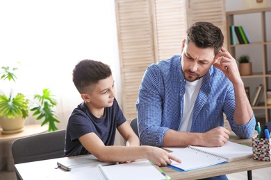 Dad helping his son with homework in room