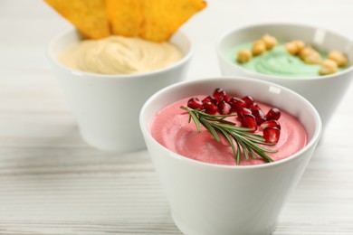 Different kinds of tasty hummus on white wooden table, closeup. Space for text