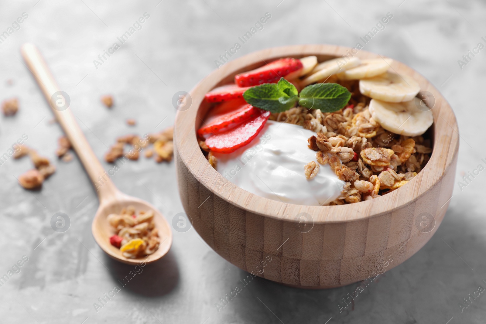 Photo of Tasty granola in bowl served on gray table, closeup