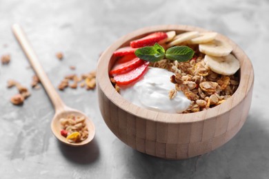 Photo of Tasty granola in bowl served on gray table, closeup