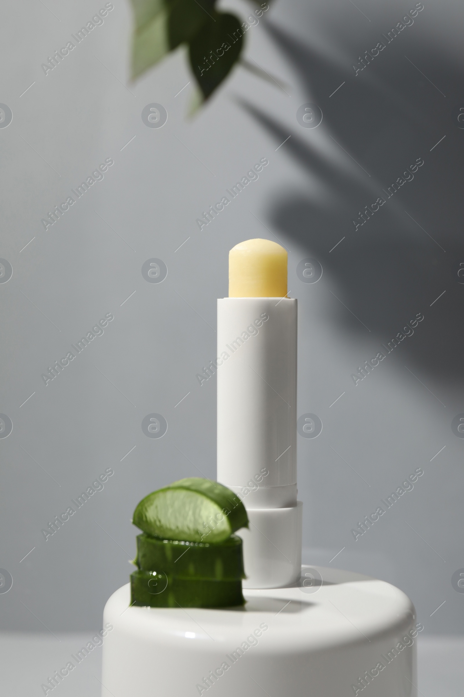 Photo of Hygienic lipstick and cut aloe vera leaf on light table