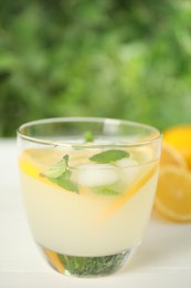 Cool freshly made lemonade in glass on white table