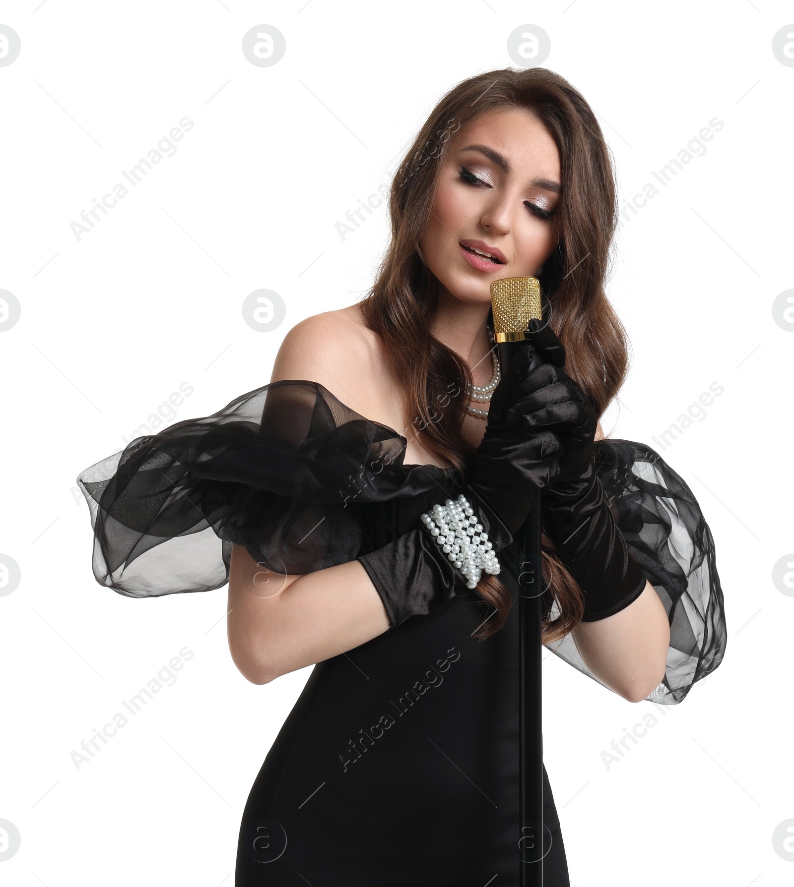 Photo of Beautiful young woman in stylish black dress with microphone singing on white background