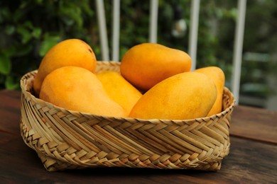 Photo of Delicious ripe juicy mangos on wooden table