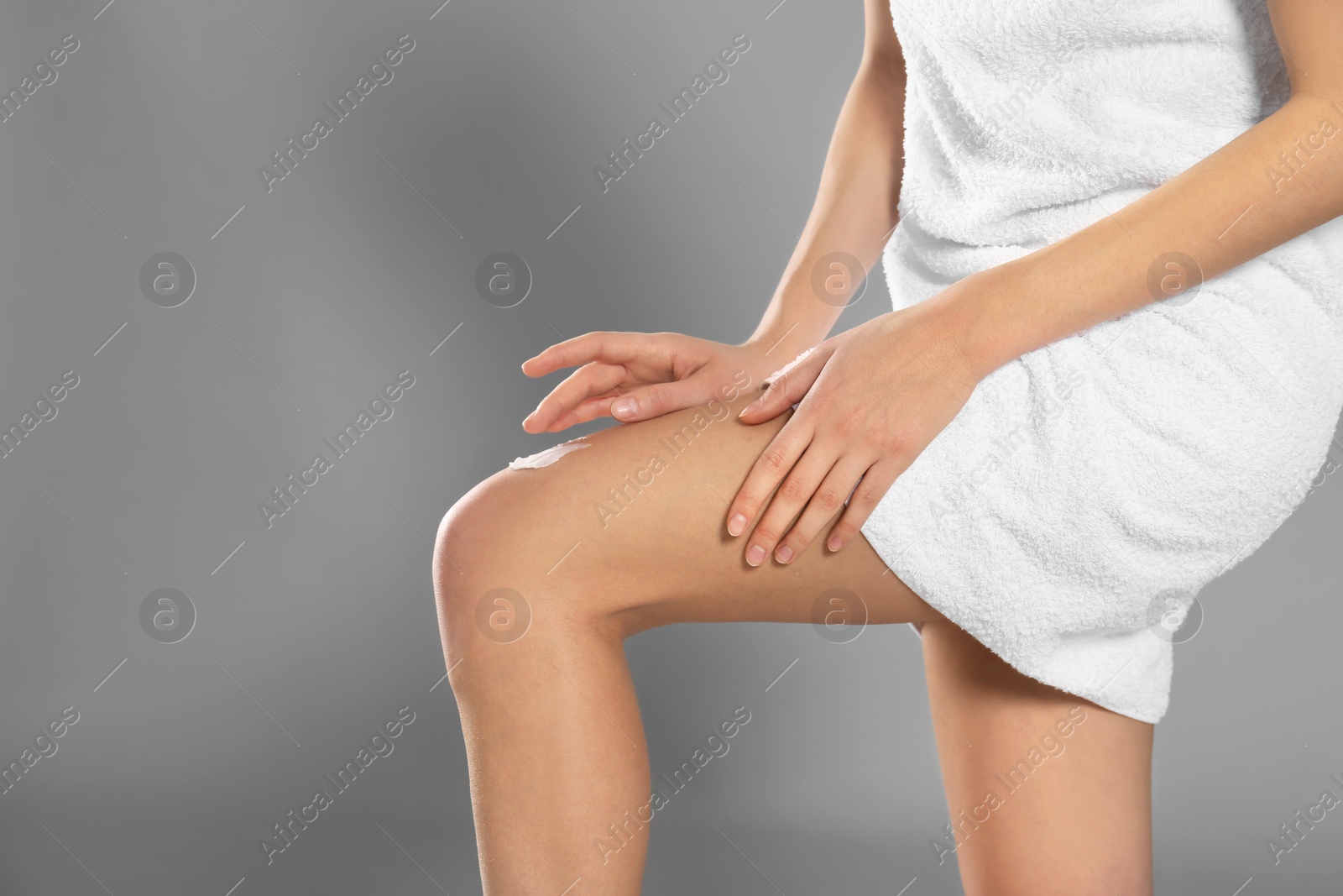 Photo of Young woman applying body cream on color background