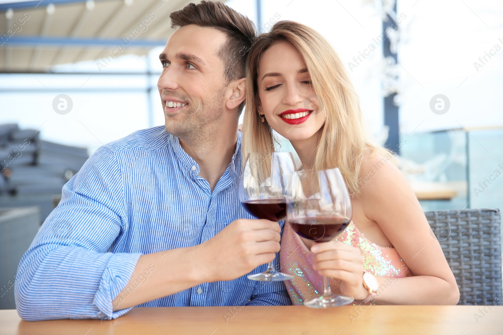 Photo of Young romantic couple with glasses of red wine at table