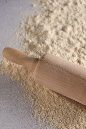 Photo of Rolling pin and scattered flour on light textured table, closeup