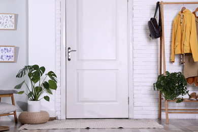 Photo of Hallway interior with stylish furniture, clothes and plants