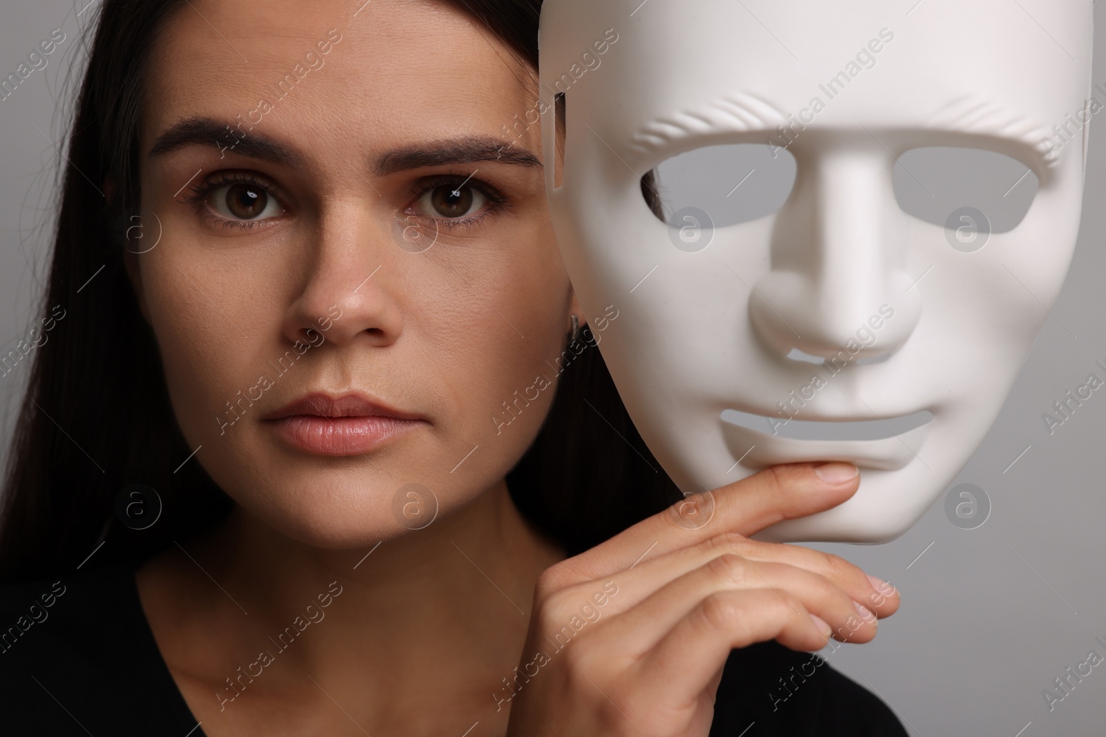 Photo of Multiple personality concept. Woman with mask on grey background