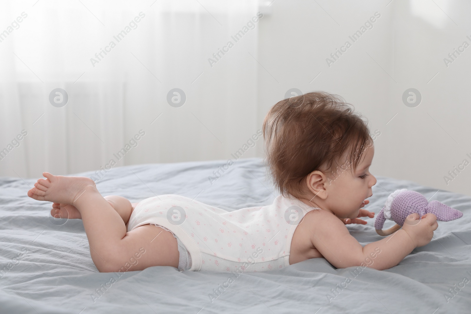 Photo of Cute little baby with toy on bed