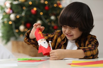 Cute little boy making paper Saint Nicholas toy at home