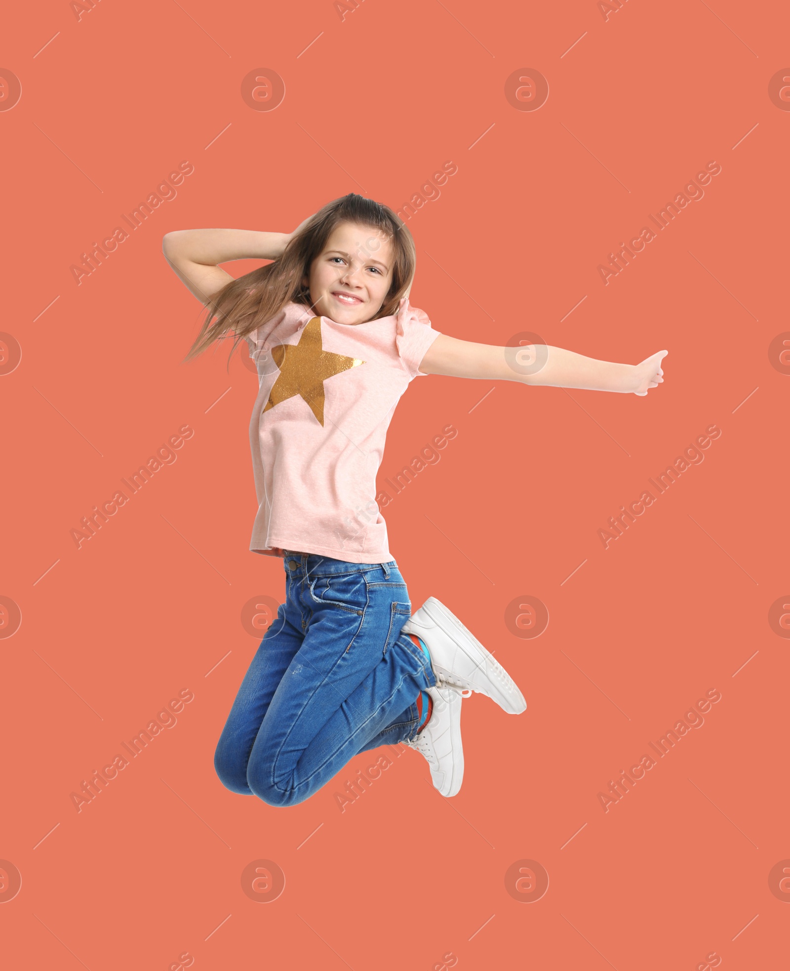 Image of Happy cute girl jumping on coral background