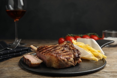 Tasty grilled beef steak and French fries on wooden table