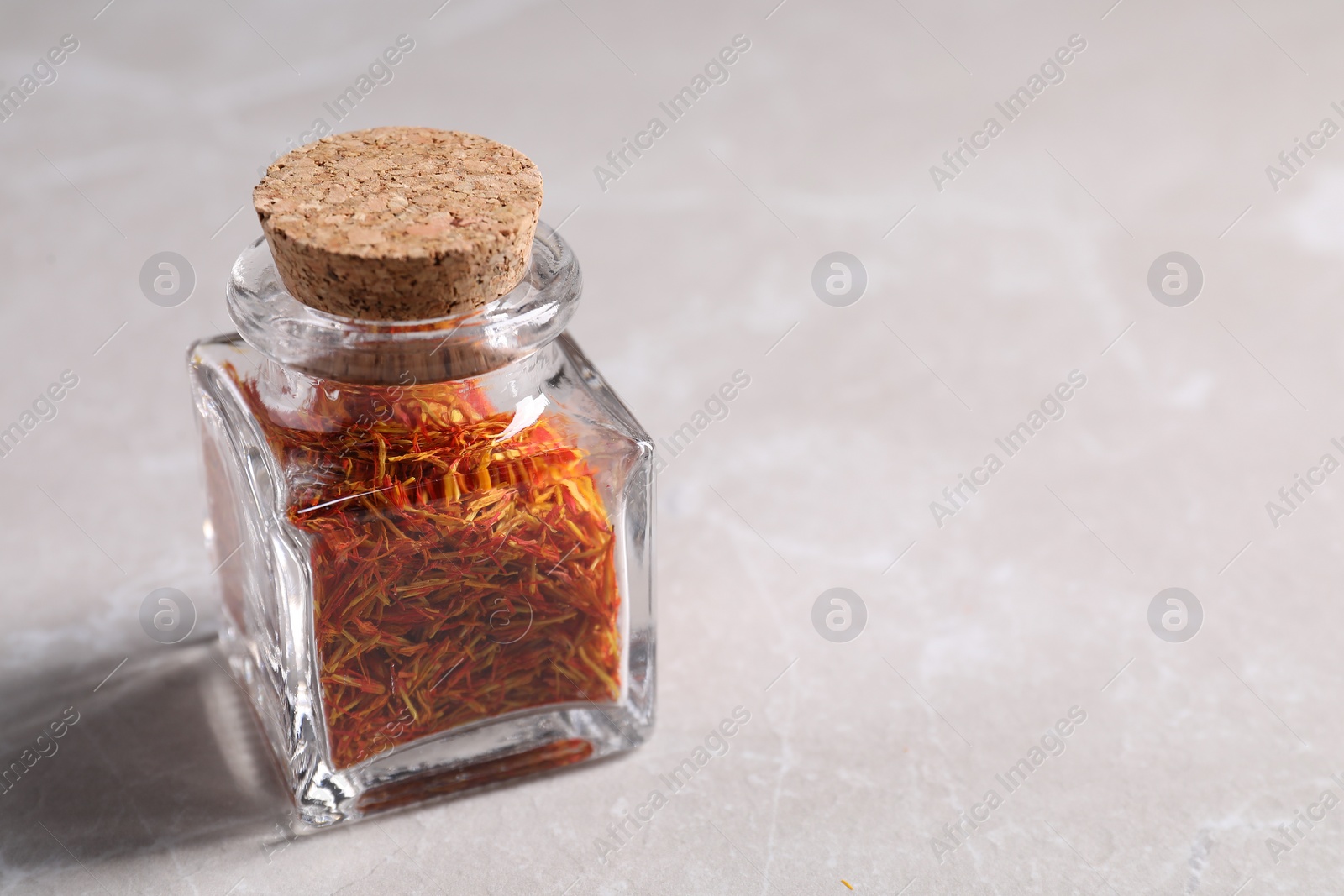 Photo of Aromatic saffron and glass jar on light gray table, space for text