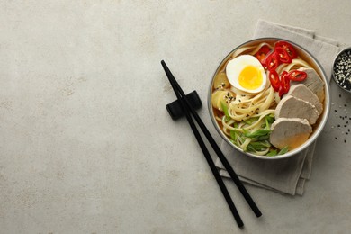 Photo of Delicious ramen in bowl and chopsticks on light textured table, flat lay with space for text. Noodle soup