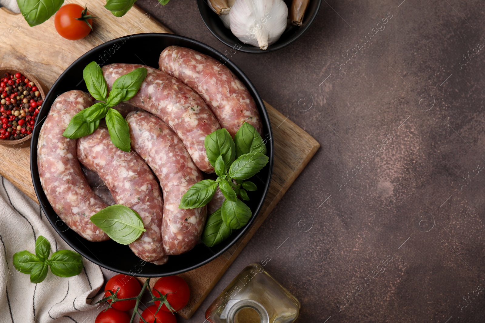 Photo of Raw homemade sausages and different products on grey table, flat lay. Space for text
