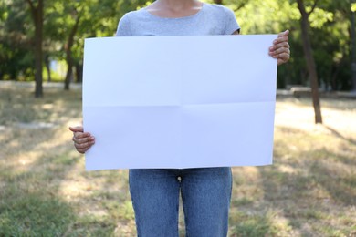 Photo of Woman holding blank poster outdoors, closeup. Mockup for design	