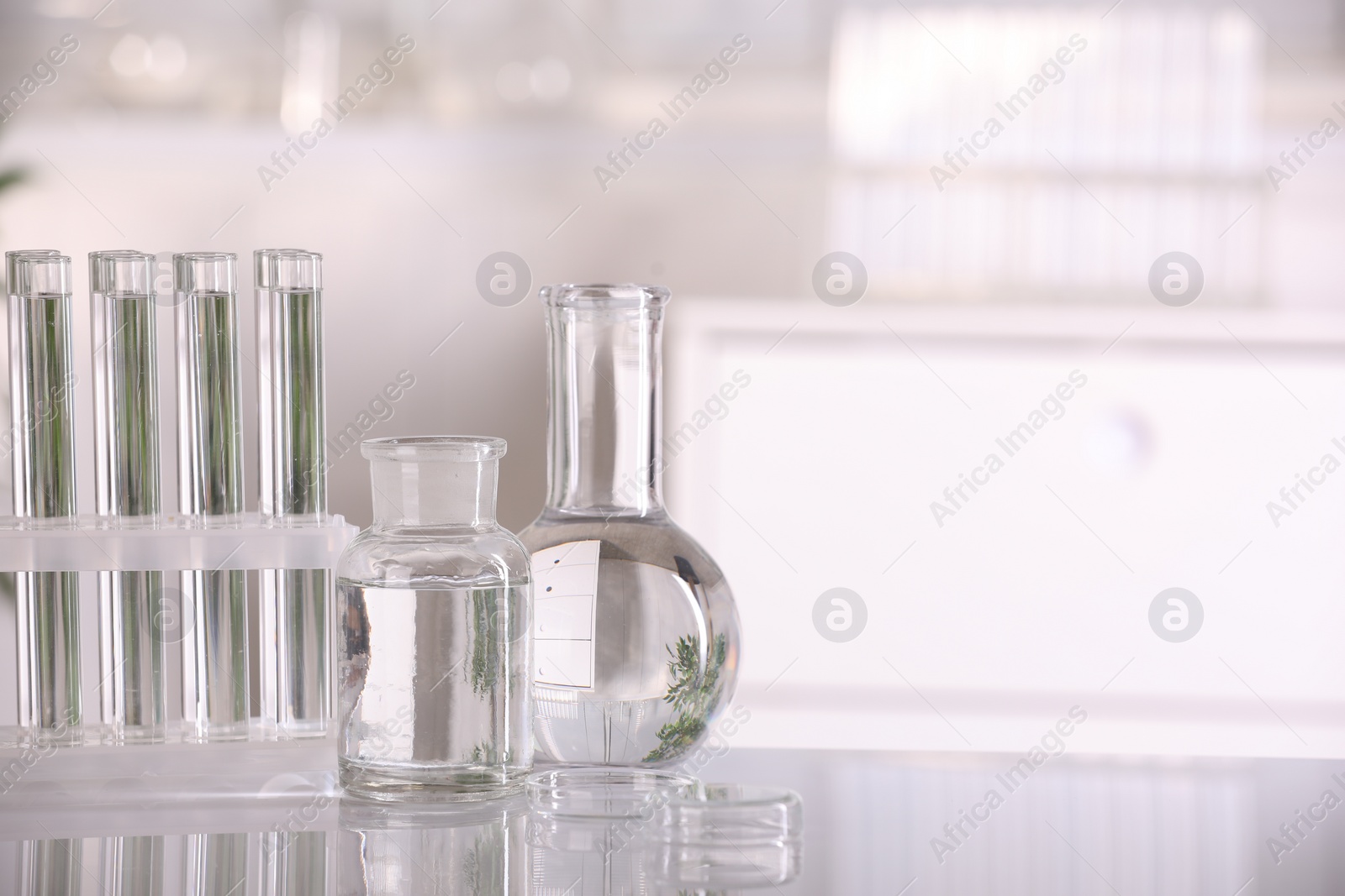 Photo of Laboratory analysis. Different glassware with liquid on white table indoors, space for text