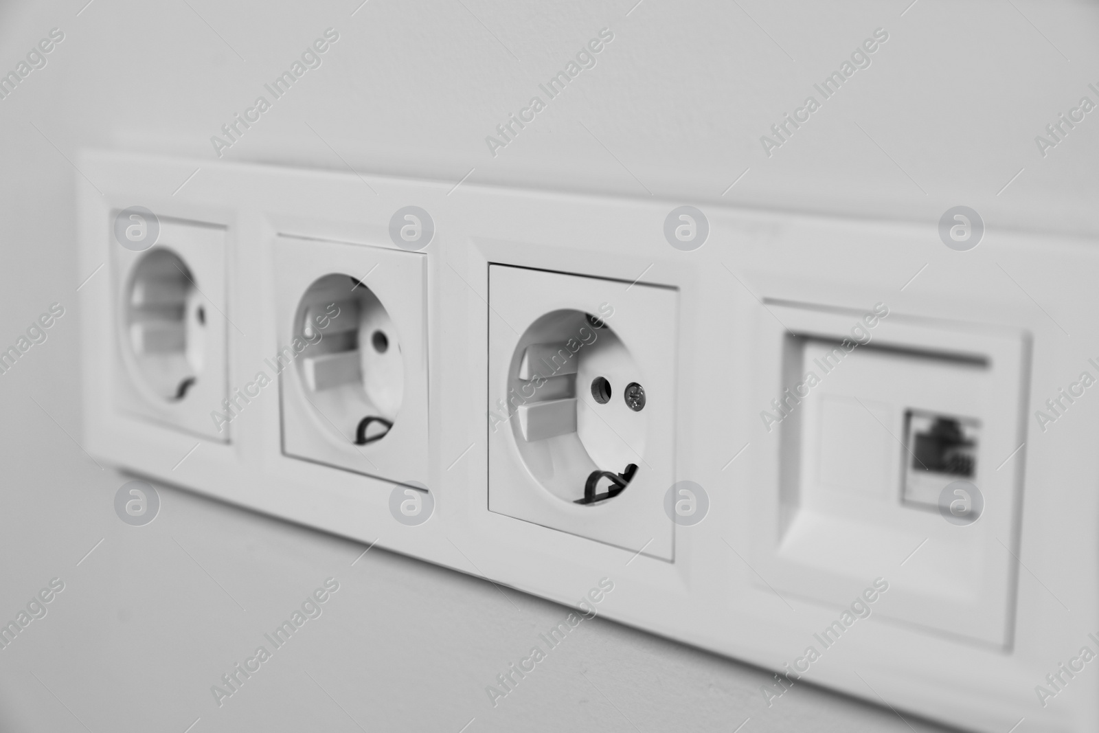 Photo of Power sockets on white wall, closeup. Electrical supply