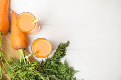 Photo of Freshly made carrot juice on white wooden table, flat lay. Space for text