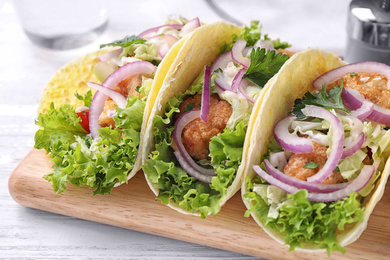 Yummy fish tacos served on white wooden table, closeup