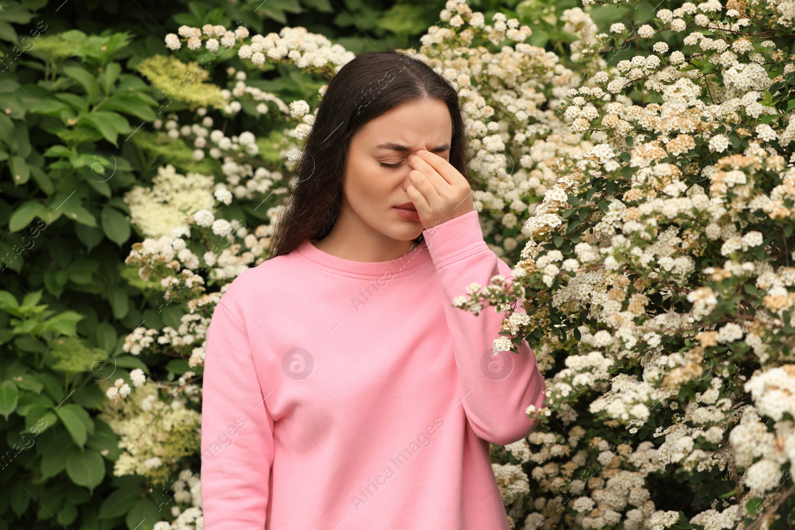 Photo of Woman suffering from seasonal pollen allergy near blossoming tree on spring day