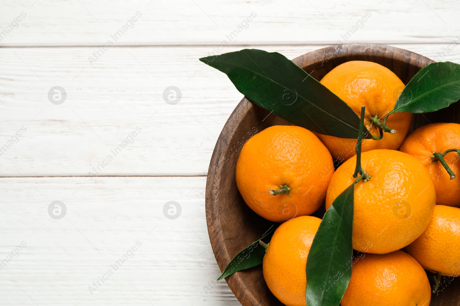 Photo of Fresh ripe tangerines with leaves and space for text on white wooden table, top view. Citrus fruit