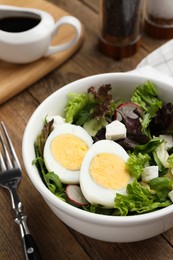 Photo of Delicious salad with boiled egg, feta cheese and vegetables on wooden table, closeup