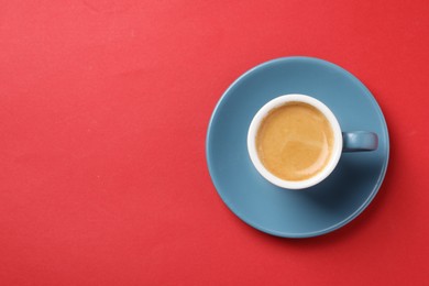 Photo of Aromatic coffee in cup on red background, top view. Space for text