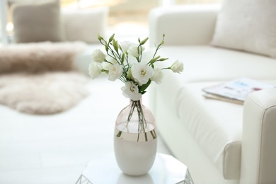Photo of Vase with fresh flowers on white table in living room