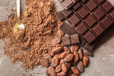 Delicious chocolate, cocoa powder and beans on table, top view