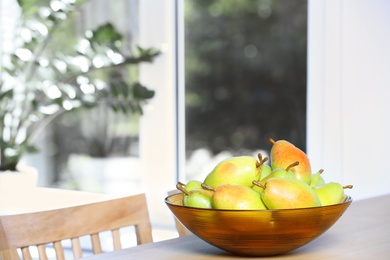 Photo of Fresh ripe pears on wooden table indoors. Space for text