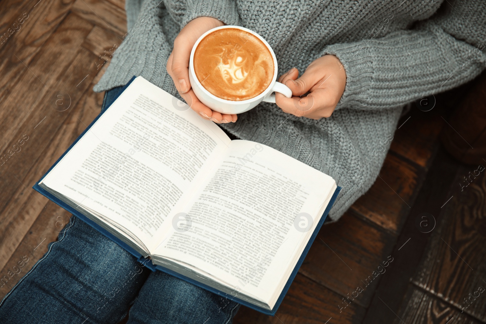 Photo of Woman with cup of coffee reading book at home, closeup