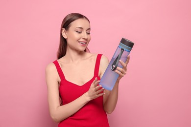Photo of Beautiful young woman with transparent bottle for water on pink background
