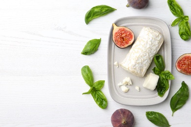 Delicious goat cheese with figs and basil on white wooden table, flat lay. Space for text