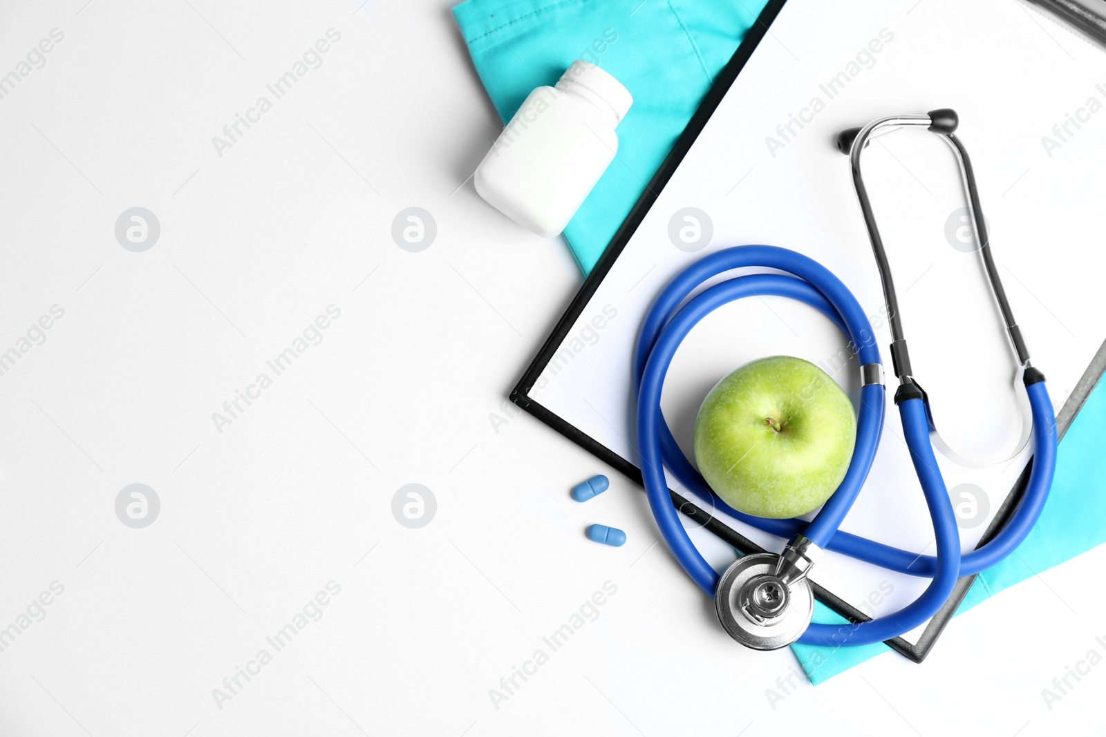 Photo of Flat lay composition with stethoscope, apple and clipboard on light background. Medical equipment