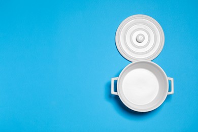 White empty pot and lid on light blue background, flat lay. Space for text